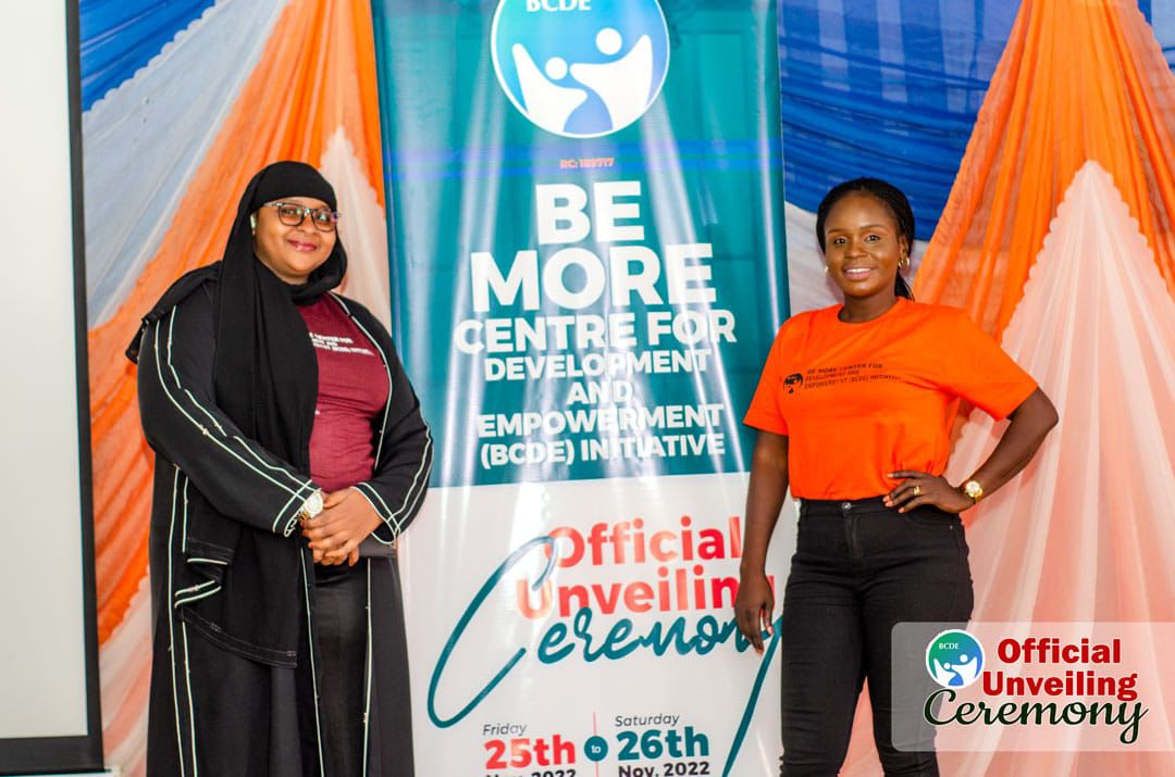 Two women posing beside the ceremony banner