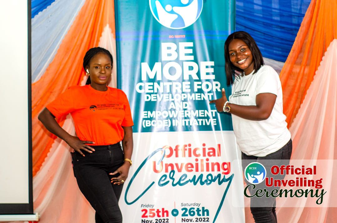 Two women posing and smiling beside the banner